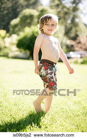 Stock Image - Portrait of young boy in field, smiling. Fotosearch