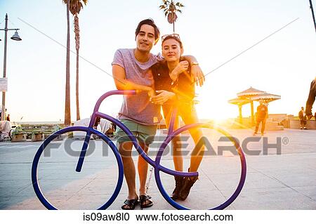 Portrait of young couple leaning against bicycle sculpture at coast, Venice Beach, California, USA View Large Photo Image Stock Image - Portrait of young couple leaning against bicycle sculpture at coast, Venice Beach, California, USA. Fotosearch