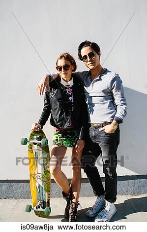 Portrait of young couple outdoors, woman holding skateboard View Large Photo Image Stock Image - Portrait of young couple outdoors, woman holding skateboard. Fotosearch