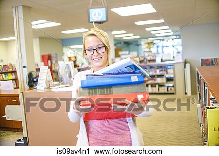 Portrait of young female librarian carrying pile of books View Large Photo Image Stock Image - Portrait of young female librarian carrying pile of books. Fotosearch