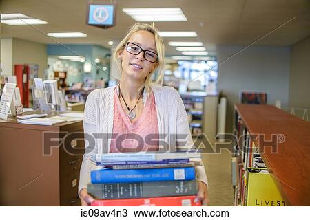 Portrait of young female librarian carrying stack of books View Large Photo Image Stock Image - Portrait of young female librarian carrying stack of books. Fotosearch