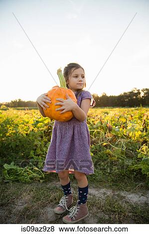 Portrait of young girl, holding pumpkin View Large Photo Image Stock Photo - Portrait of young girl, holding pumpkin. Fotosearch