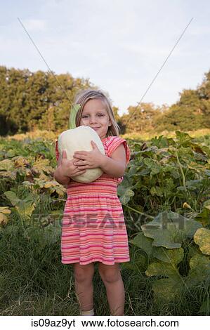 Stock Photograph - Portrait of young girl, holding pumpkin. Fotosearch