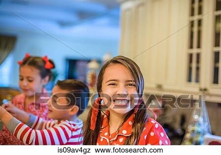 Portrait of young girl in kitchen, brother and sister in background View Large Photo Image Stock Photo - Portrait of young girl in kitchen, brother and sister in background. Fotosearch