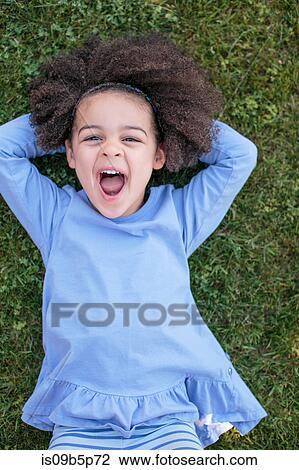 Portrait of young girl lying on grass, laughing, overhead view View Large Photo Image Stock Image - Portrait of young girl lying on grass, laughing, overhead view. Fotosearch