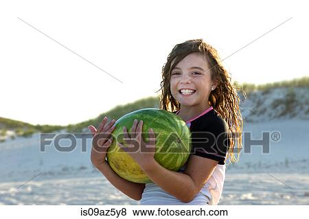 Portrait of young girl on beach, holding melon, smiling View Large Photo Image Stock Photo - Portrait of young girl on beach, holding melon, smiling. Fotosearch