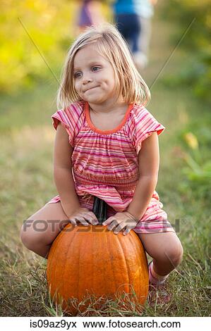 Portrait of young girl, sitting on pumpkin View Large Photo Image Stock Photo - Portrait of young girl, sitting on pumpkin. Fotosearch
