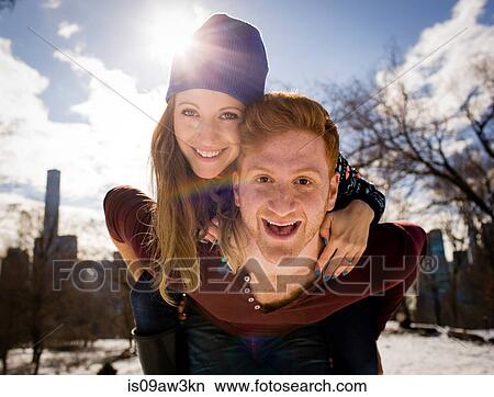 Portrait of young man giving girlfriend a piggy back in snowy Central Park, New York, USA View Large Photo Image Picture - Portrait of young man giving girlfriend a piggy back in snowy Central Park, New York, USA. Fotosearch