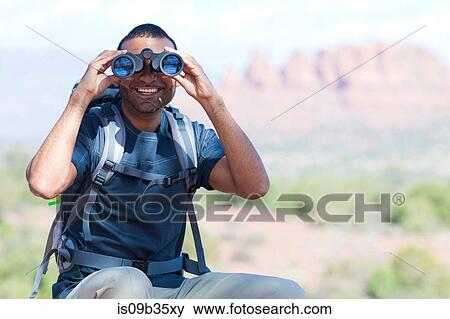Portrait of young man looking through binoculars, Sedona, Arizona, USA View Large Photo Image Stock Photo - Portrait of young man looking through binoculars, Sedona, Arizona, USA. Fotosearch