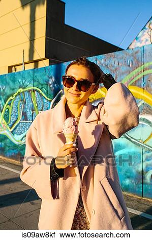 Portrait of young stylish woman eating ice cream cone in front of graffiti wall, Venice Beach, California, USA View Large Photo Image Stock Image - Portrait of young stylish woman eating ice cream cone in front of graffiti wall, Venice Beach, California, USA. Fotosearch
