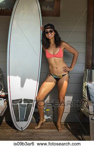Portrait of young surfing woman standing on porch, Rockaway Beach, New York State, USA View Large Photo Image Stock Photograph - Portrait of young surfing woman standing on porch, Rockaway Beach, New York State, USA. Fotosearch
