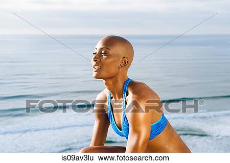 Stock Photograph - Portrait of young woman beside sea, sun falling on face. Fotosearch