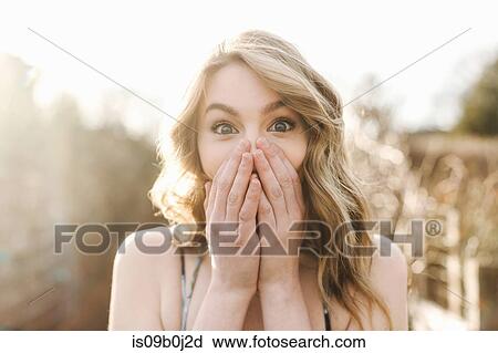 Portrait of young woman covering mouth with hands View Large Photo Image Stock Image - Portrait of young woman covering mouth with hands. Fotosearch