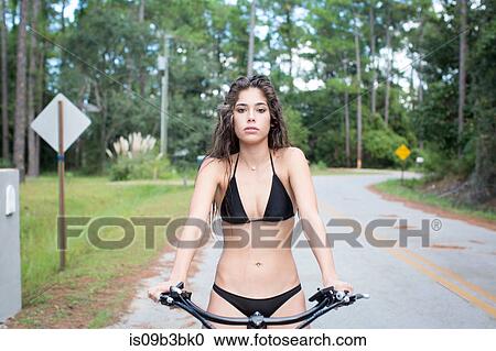 Stock Image - Portrait of young woman in bikini on bicycle, Santa Rosa Beach, Florida, USA. Fotosearch