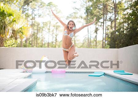 Portrait of young woman jumping mid air into swimming pool, Santa Rosa Beach, Florida, USA View Large Photo Image Stock Photo - Portrait of young woman jumping mid air into swimming pool, Santa Rosa Beach, Florida, USA. Fotosearch