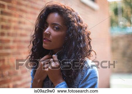 Portrait of young woman outdoors, pulling collar up View Large Photo Image Stock Image - Portrait of young woman outdoors, pulling collar up. Fotosearch