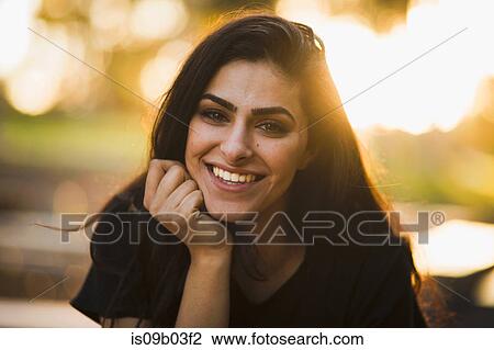 Stock Image - Portrait of young woman, outdoors, smiling. Fotosearch