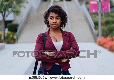 Portrait of young woman standing outdoors, arms folded View Large Photo Image Stock Photo - Portrait of young woman standing outdoors, arms folded. Fotosearch