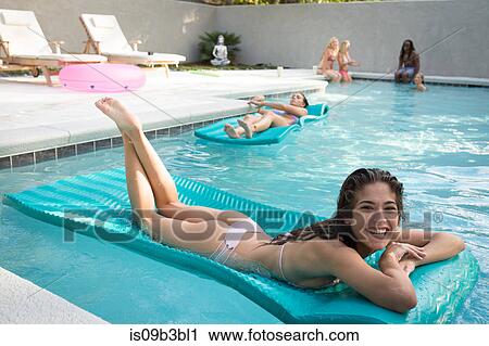 Stock Image - Portrait of young woman sunbathing in swimming pool, Santa Rosa Beach, Florida, USA. Fotosearch