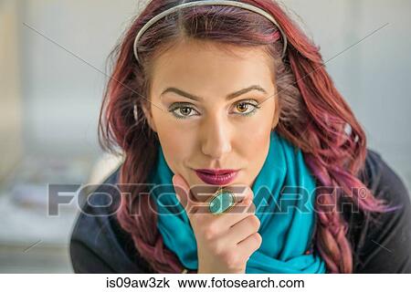 Stock Image - Portrait of young woman with hand on chin. Fotosearch