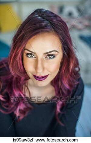 Stock Image - Portrait of young woman with pink hair, smiling. Fotosearch