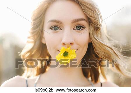 Portrait of young woman with yellow flower in mouth View Large Photo Image Stock Image - Portrait of young woman with yellow flower in mouth. Fotosearch
