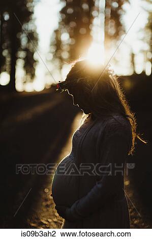 Pregnant woman in sunlight touching stomach View Large Photo Image Stock Image - Pregnant woman in sunlight touching stomach. Fotosearch