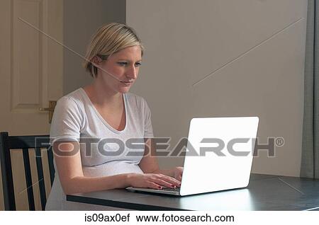 Pregnant woman sitting at table, using laptop computer View Large Photo Image Stock Image - Pregnant woman sitting at table, using laptop computer. Fotosearch