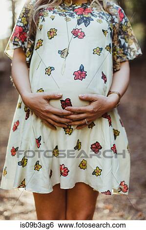 Stock Photograph - Pregnant woman touching stomach. Fotosearch
