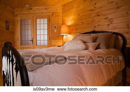 Queen size bed with cast iron headboard and footboard in the master bedroom on the upstairs floor inside a small cottage style log home View Large Photo Image Stock Photo - Queen size bed with cast iron headboard and footboard in the master bedroom on the upstairs floor inside a small cottage style log home. Fotosearch