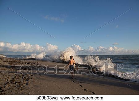 Rear view of boy exploring beach with splashing waves, Blowing Rocks Preserve, Jupiter Island, Florida, USA View Large Photo Image Stock Image - Rear view of boy exploring beach with splashing waves, Blowing Rocks Preserve, Jupiter Island, Florida, USA. Fotosearch