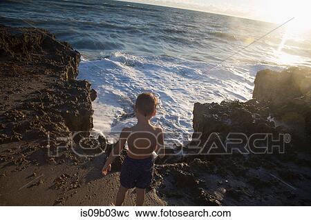 Rear view of boy watching ocean waves, Blowing Rocks Preserve, Jupiter Island, Florida, USA View Large Photo Image Stock Image - Rear view of boy watching ocean waves, Blowing Rocks Preserve, Jupiter Island, Florida, USA. Fotosearch