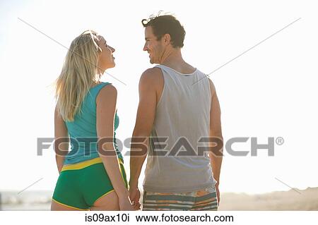Rear view of couple on beach face to face smiling View Large Photo Image Stock Image - Rear view of couple on beach face to face smiling. Fotosearch