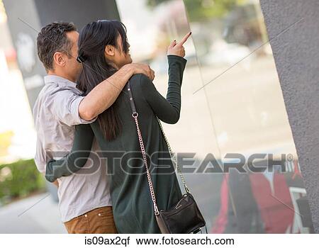Rear view of couple window shopping View Large Photo Image Stock Image - Rear view of couple window shopping. Fotosearch