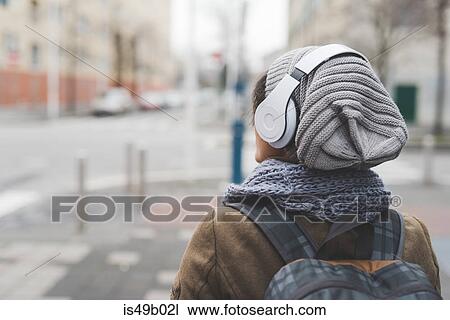 Rear view of female backpacker listening to headphones in empty city View Large Photo Image Stock Image - Rear view of female backpacker listening to headphones in empty city. Fotosearch