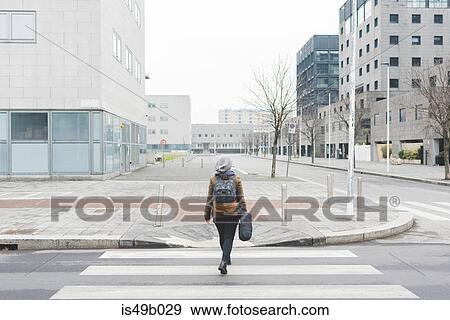Rear view of female backpacker walking over city pedestrian crossing View Large Photo Image Stock Photo - Rear view of female backpacker walking over city pedestrian crossing. Fotosearch