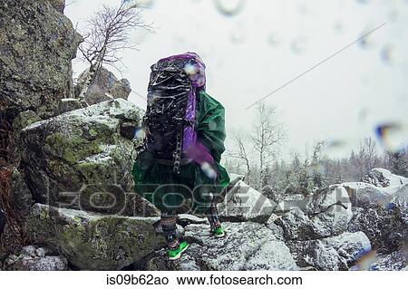 Rear view of female hiker in waterproof clothing looking out from mountain in snowstorm View Large Photo Image Picture - Rear view of female hiker in waterproof clothing looking out from mountain in snowstorm. Fotosearch