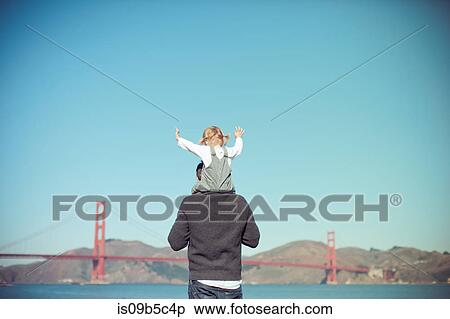 Rear view of female toddler on father's shoulders looking out at golden gate bridge, San Francisco, USA View Large Photo Image Stock Photography - Rear view of female toddler on father's shoulders looking out at golden gate bridge, San Francisco, USA. Fotosearch