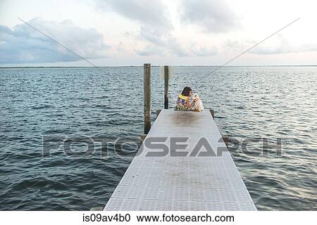 Rear view of girl sitting on sea pier petting dog View Large Photo Image Stock Image - Rear view of girl sitting on sea pier petting dog. Fotosearch