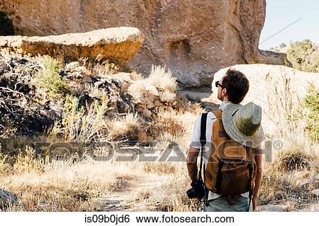 Rear view of hiker looking up at rock face, Malibu Canyon, California, USA View Large Photo Image Stock Photograph - Rear view of hiker looking up at rock face, Malibu Canyon, California, USA. Fotosearch