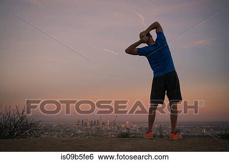 Stock Photograph - Rear view of jogger stretching at dusk, Runyon Canyon, Los Angeles, California, USA. Fotosearch