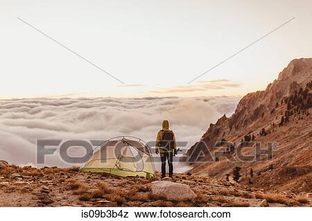 Stock Photo - Rear view of male hiker looking out over the clouds, Mineral King, Sequoia National Park, California, USA. Fotosearch