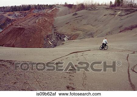 Rear view of male mountain biker mountain biking down quarry hill View Large Photo Image Stock Image - Rear view of male mountain biker mountain biking down quarry hill. Fotosearch