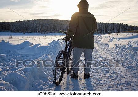 Rear view of male mountain biker watching sunset over snow covered landscape View Large Photo Image Stock Image - Rear view of male mountain biker watching sunset over snow covered landscape. Fotosearch