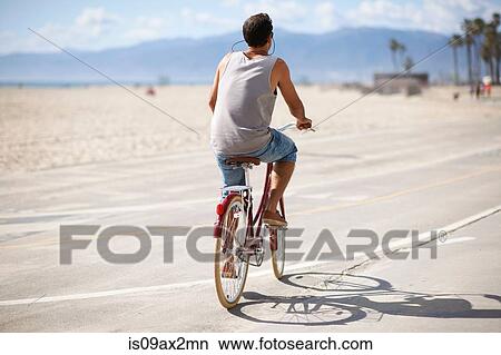 Rear view of man cycling at Venice Beach, Los Angeles, California, USA View Large Photo Image Picture - Rear view of man cycling at Venice Beach, Los Angeles, California, USA. Fotosearch