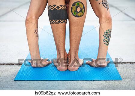 Stock Photo - Rear view of man practicing yoga, standing on yoga mat with hands on floor. Fotosearch