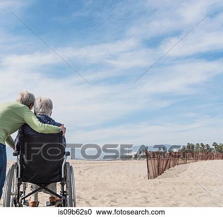 Rear view of senior man in wheelchair with wife looking out from beach, Santa Monica, California, USA View Large Photo Image Stock Image - Rear view of senior man in wheelchair with wife looking out from beach, Santa Monica, California, USA. Fotosearch