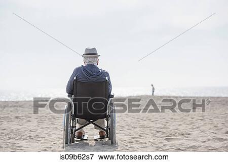 Rear view of senior man in wheelchair looking out from beach, Santa Monica, California, USA View Large Photo Image Stock Photo - Rear view of senior man in wheelchair looking out from beach, Santa Monica, California, USA. Fotosearch