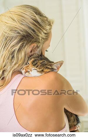 Stock Photo - Rear view of woman cuddling cat. Fotosearch