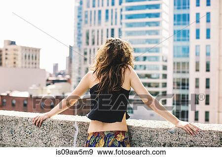 Rear view of woman on rooftop wearing crop top looking away at view, Boston, Massachusetts, USA View Large Photo Image Stock Photo - Rear view of woman on rooftop wearing crop top looking away at view, Boston, Massachusetts, USA. Fotosearch